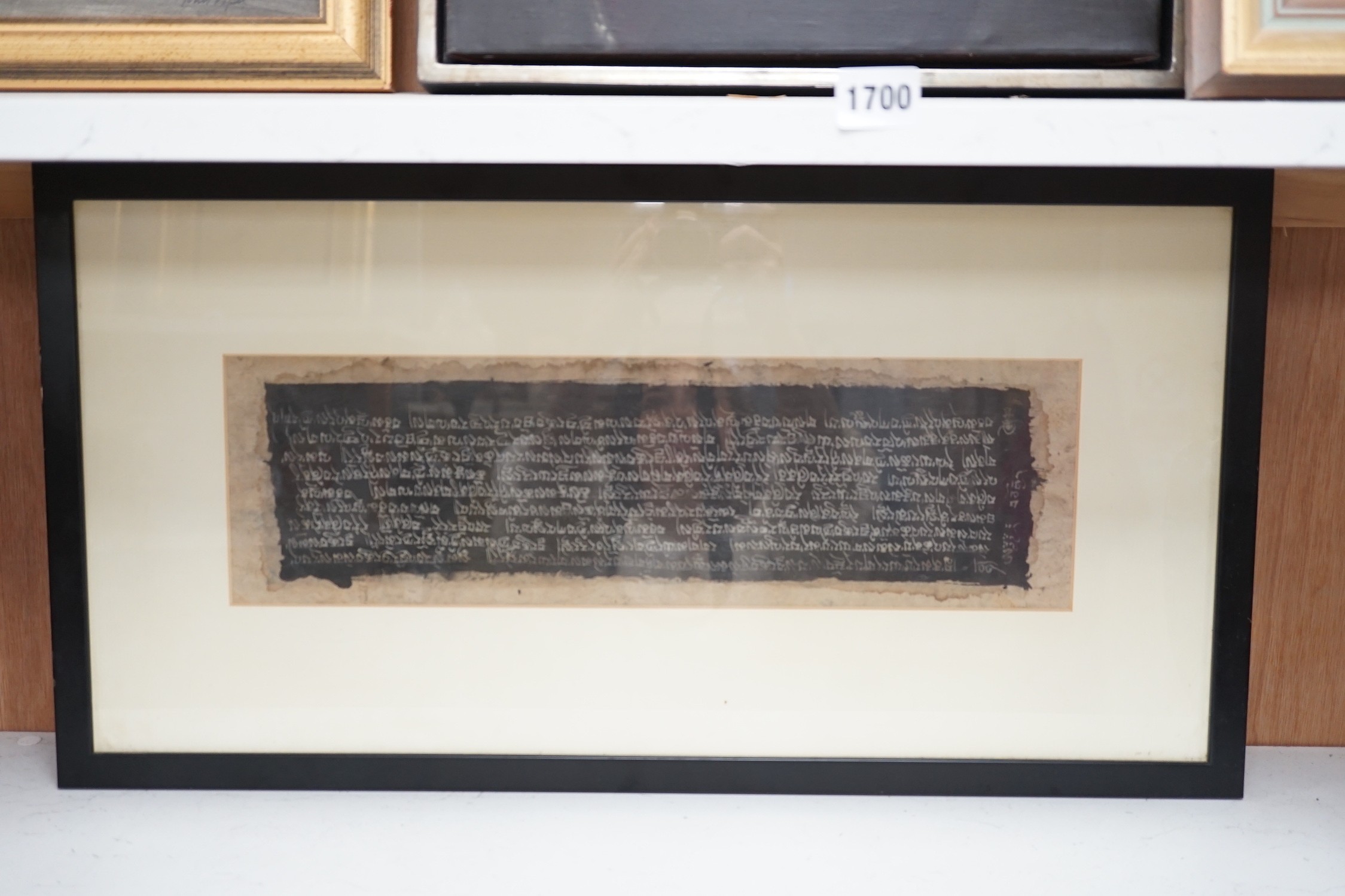 A framed Tibetan Sanskrit sutra panel, 45cms x 13cms.